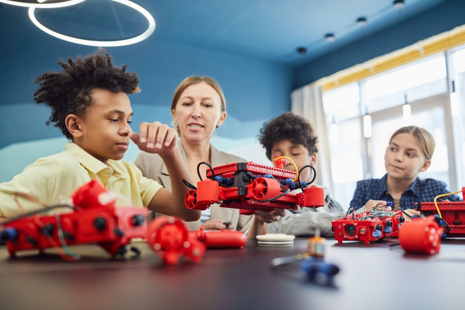 Children collaborating on a robotics project with their teacher